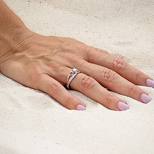 Hand with engagement ring on sand