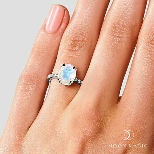 Moonstone ring with diamonds on a hand.